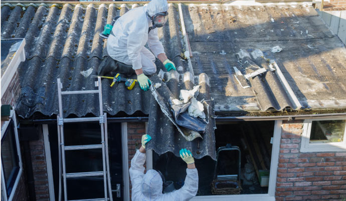 Person removing asbestos roofing material