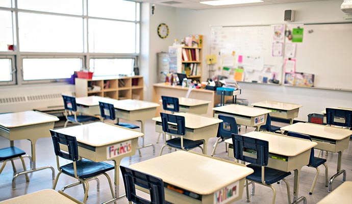 Well-organized empty classroom with desks, chairs, white-board and shelves of books