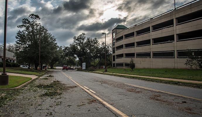 Healthcare facility parking lot and surrounding areas affected by a storm, showing debris on the road