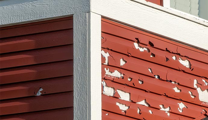 Close-up of hail-damaged hospital siding with peeling paint