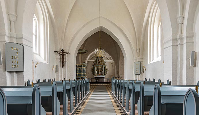 Historic church interior featuring blue wooden pews and ornate altar