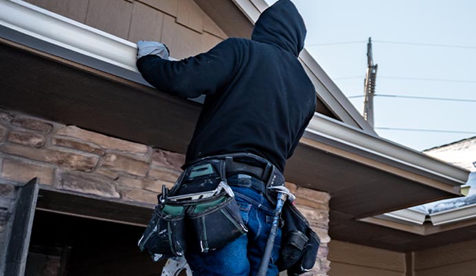A handyman is repairing gutter