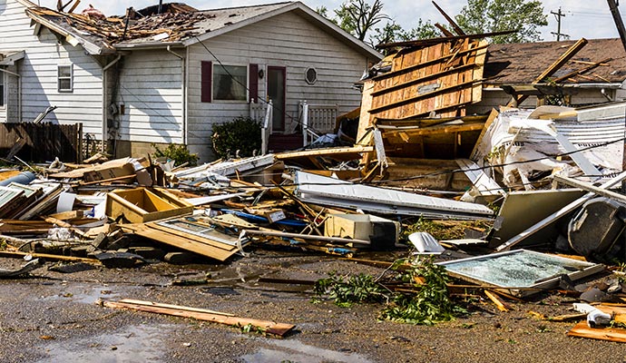 Property damaged by a hurricane with a collapsed roof and debris scattered around