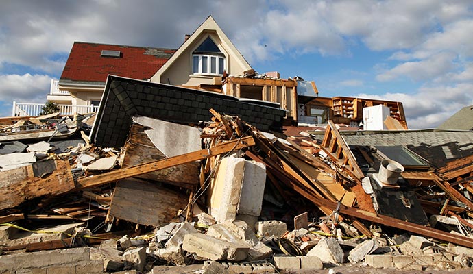 A house with severe hurricane damage and scattered debris