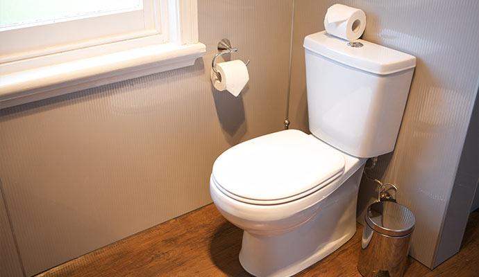 An installed white toilet on wooden floor bathroom
