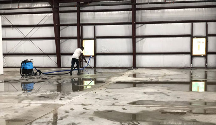 Person cleaning a water-damaged floor in a commercial space